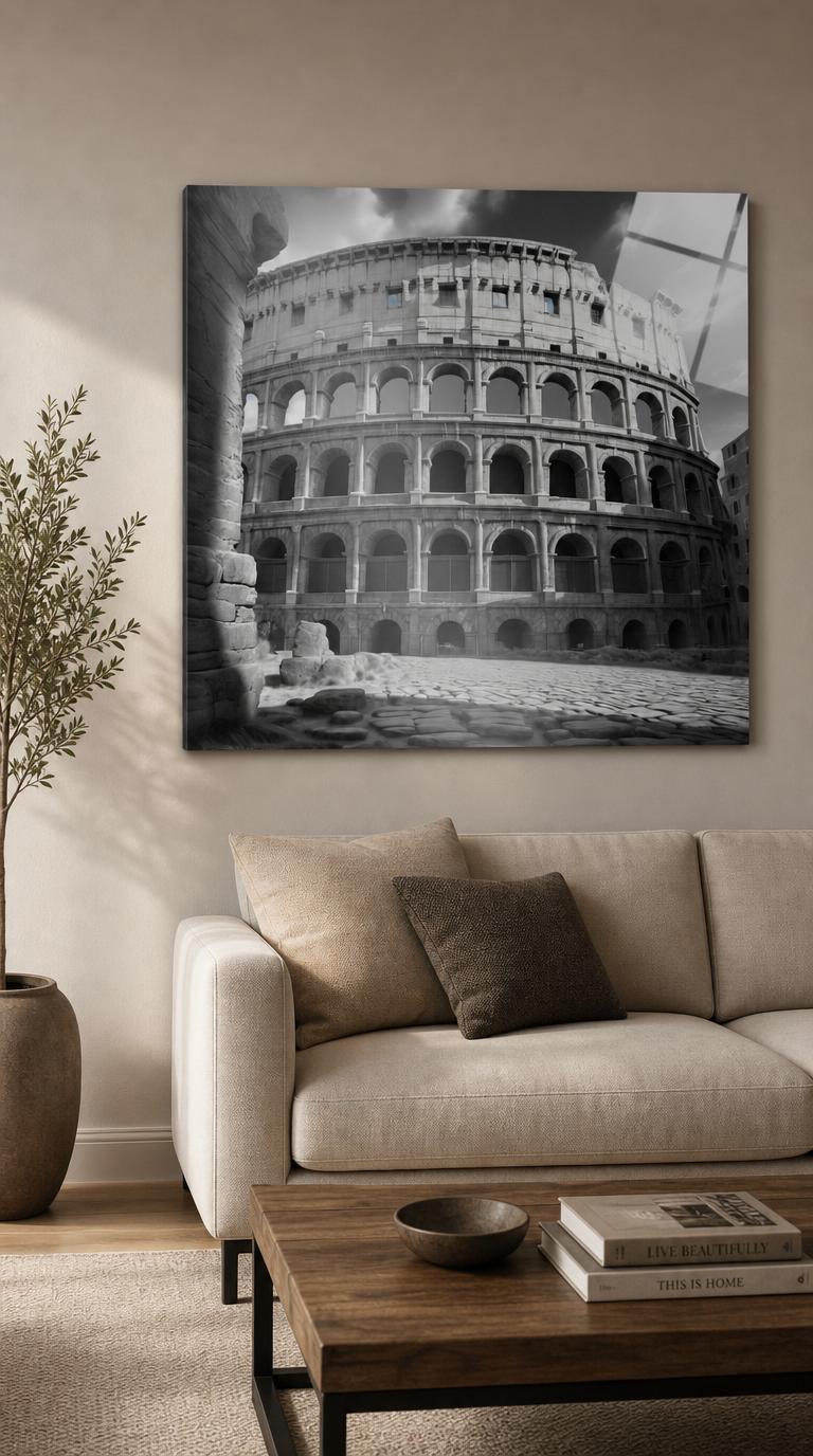 The great Roman amphitheater rises in silver and shadow, its tiered arches sweeping across a dramatic sky above a deserted cobbled forecourt.
