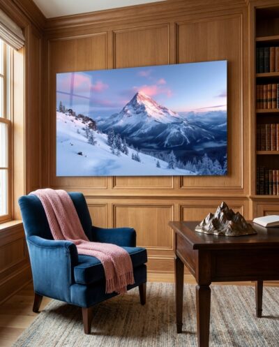 A snow-dusted peak catches the first rose-gold light of dawn while the valleys below sleep in deep blue shadow.