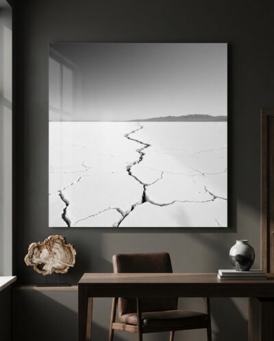 A cracked white salt flat splits along one long fissure, reaching toward a faint mountain horizon under flat, raking light.