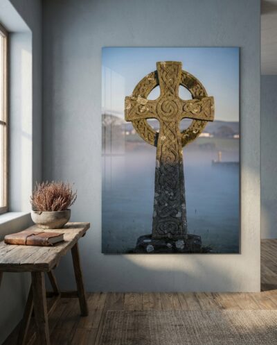 A ringed granite high cross rises from dawn mist, its carved interlace catching the first raking light across a hushed Irish valley.