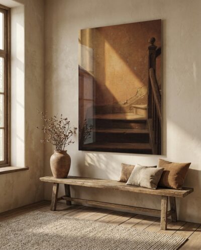 A staircase half-landing where late sun lays a long amber trapezoid across worn steps and climbs a cracked terracotta wall.