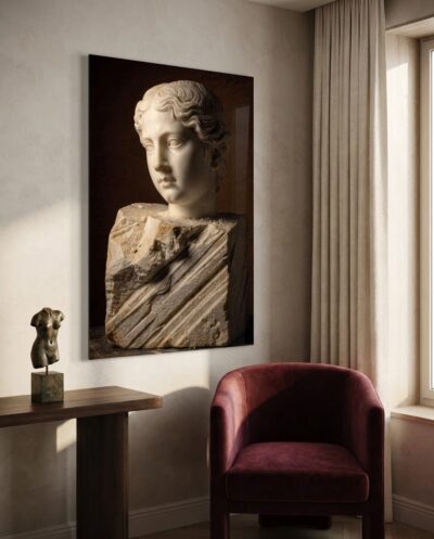 A serene idealized face emerges from raw Carrara marble, its lower block still scored by the chisel's deep tracks.
