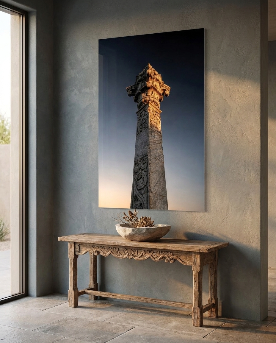 A carved stone pillar, its lotus capital catching low golden light, rises alone against a deepening twilight sky.