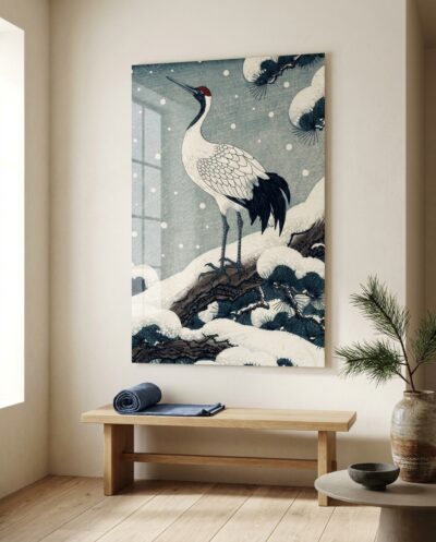 A regal red-crowned crane perches atop a snow-laden pine bough, surveying a hushed winter landscape in timeless Japanese woodblock tradition.