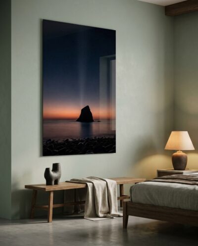 A solitary sea stack anchors a quiet shoreline as a warm terracotta horizon and faint zodiacal light herald the break of day.